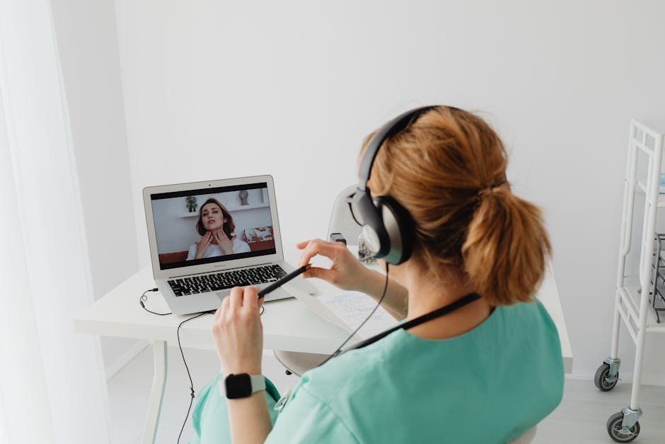 A laptop on a desk showing a secure telehealth video session with a psychiatrist, lit by morning window light